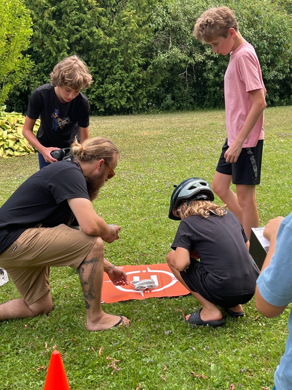 Kids learning drone flying on orange mat at DroneCamp