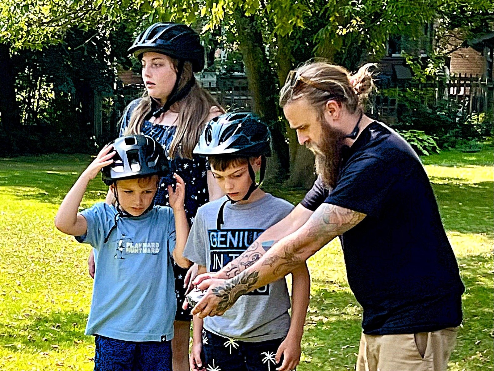 DroneCamp instructor helping kids with helmets in backyard